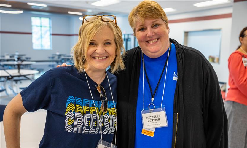 Two administrators stand together and smile